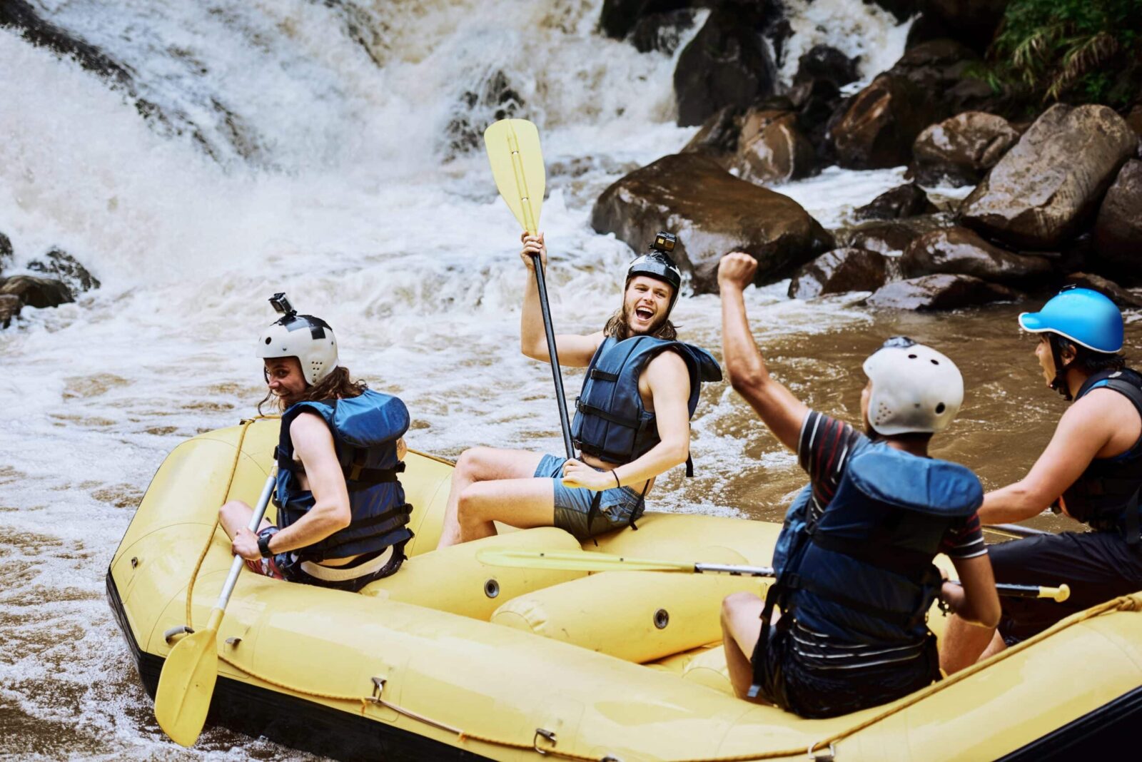 Group of four people in helmets in yellow raft having a white water adventure on the Animas River in Durango.